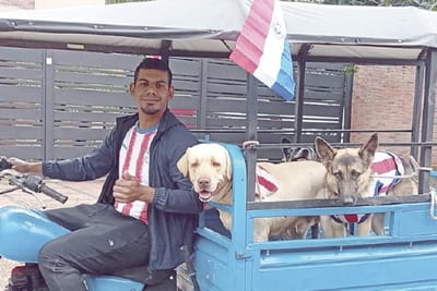 Joven recorre Ypacaraí paseando perros en un motocarro